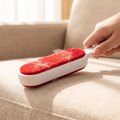 Double-sided self-cleaning lint roller being used on a sofa cushion
